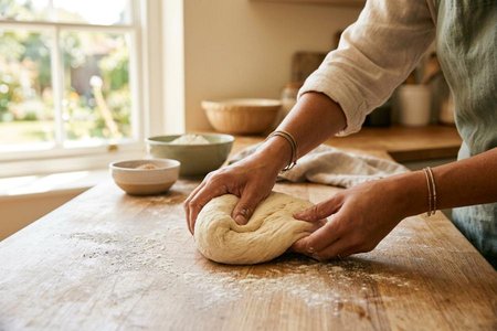 An image of the word knead as defined by to work (dough, clay, etc.) into a uniform mixture by pressing, folding, and stretching.
