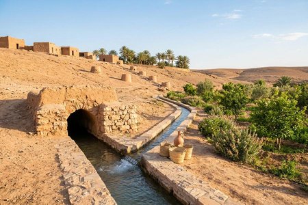 An image of the word qanat as defined by an underground aqueduct in the Middle East or North Africa through which water flows downhill from an aquifer or well to the surface.